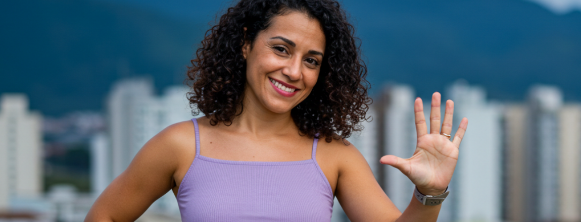 Mulher de cabelo cacheado e blusa lilás está com uma mão aberta levantada, no qual os 5 dedos fazem referência ao top 5 temáticas